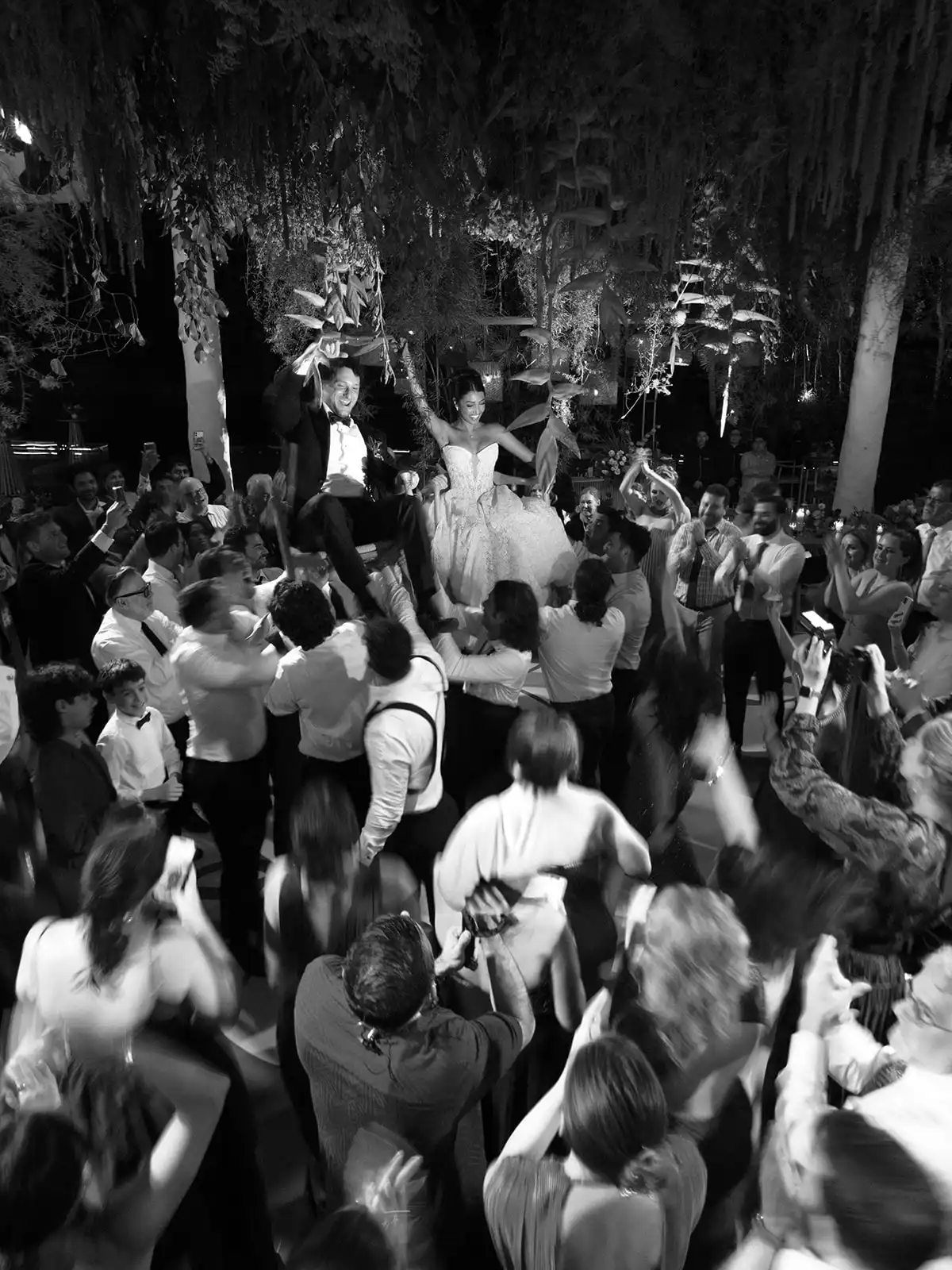 Bride and groom lifted on chairs among the guests during the party