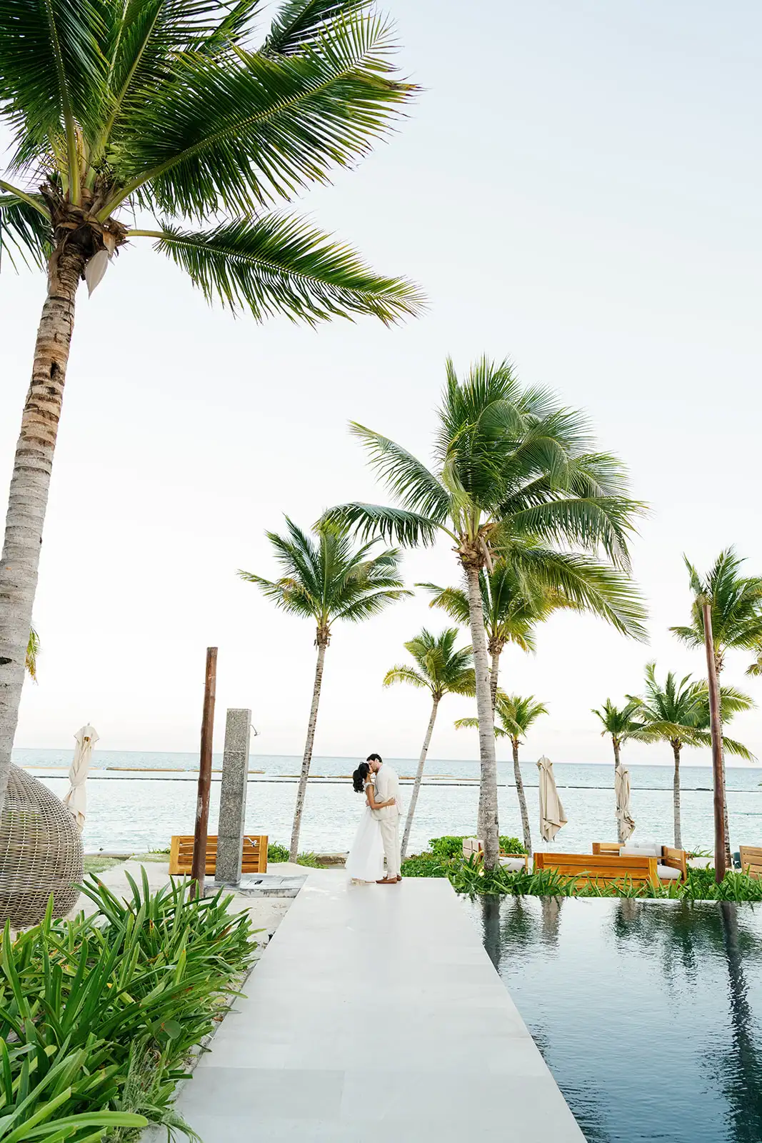 Couple embracing by the sea and the palm trees in Mayakoba, Riviera Maya
